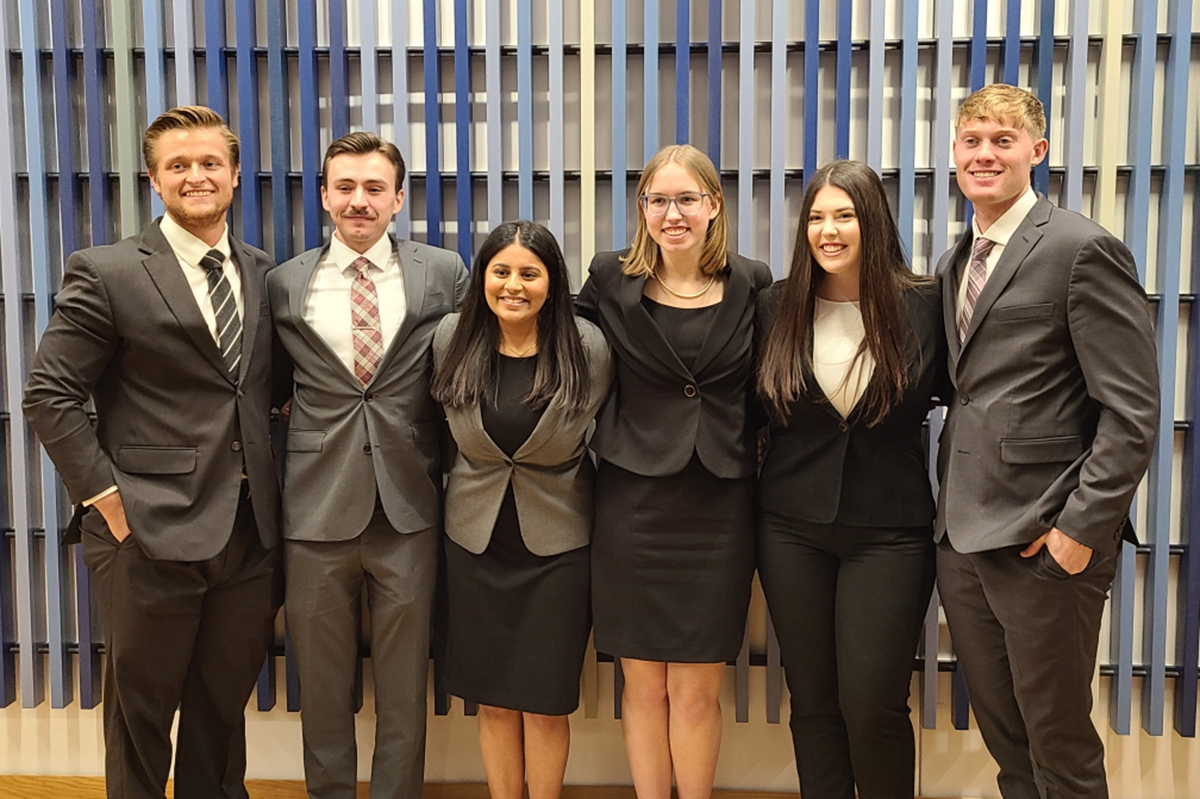college students in professional attire standing shoulder to shoulder